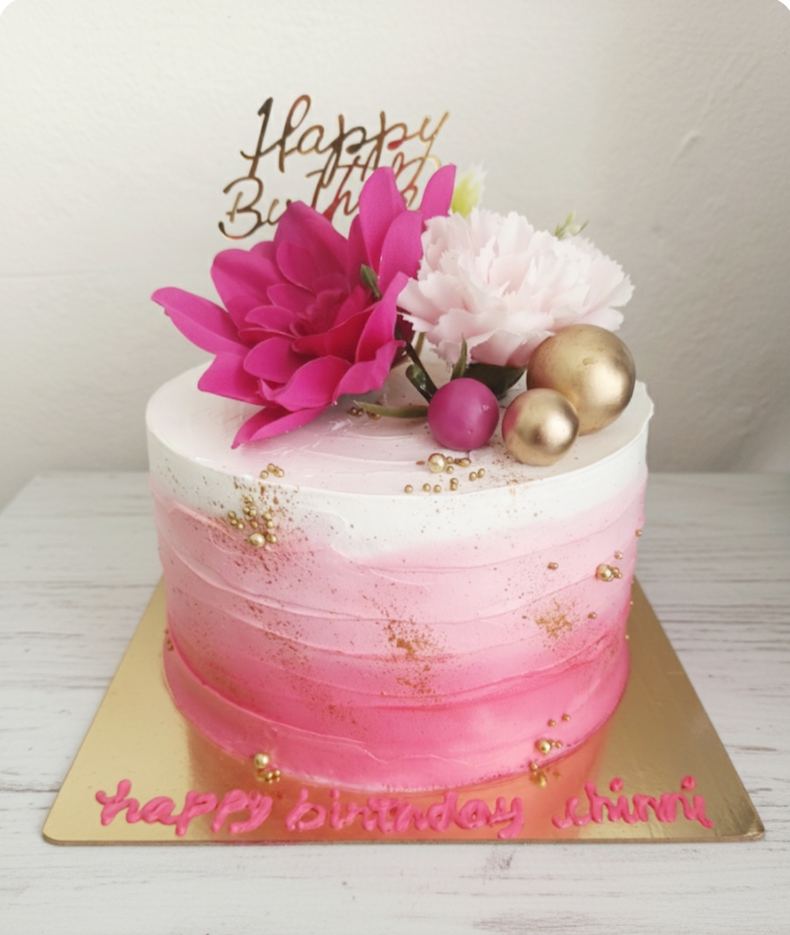 Pink ombre birthday cake decorated with fresh flowers and gold pearls