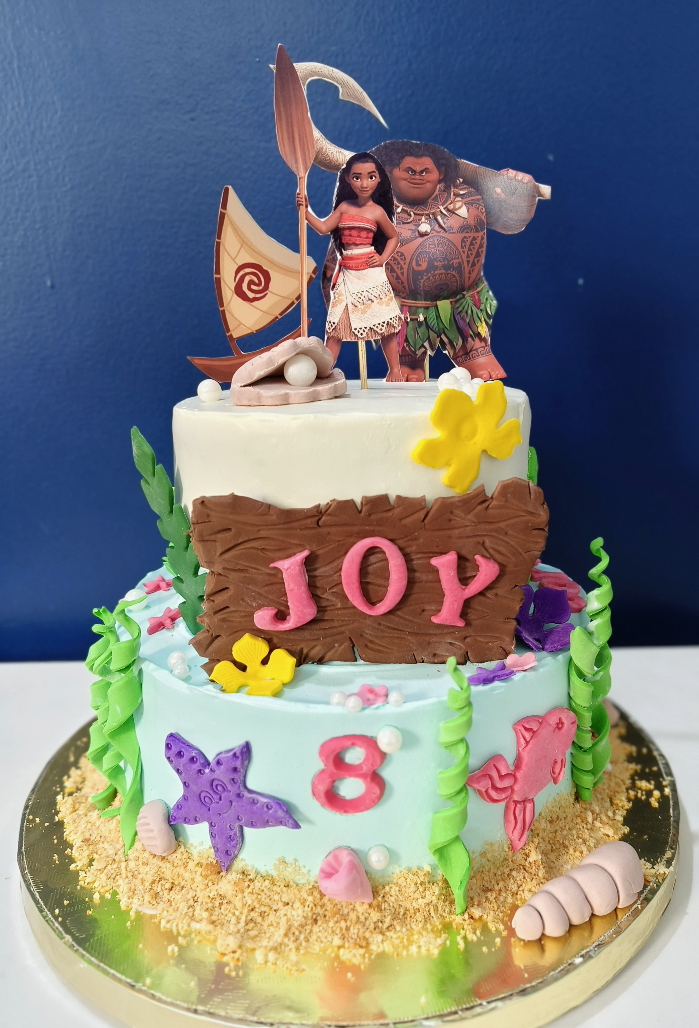 Two-tier ocean-themed birthday cake with starfish, fish, and seaweed details